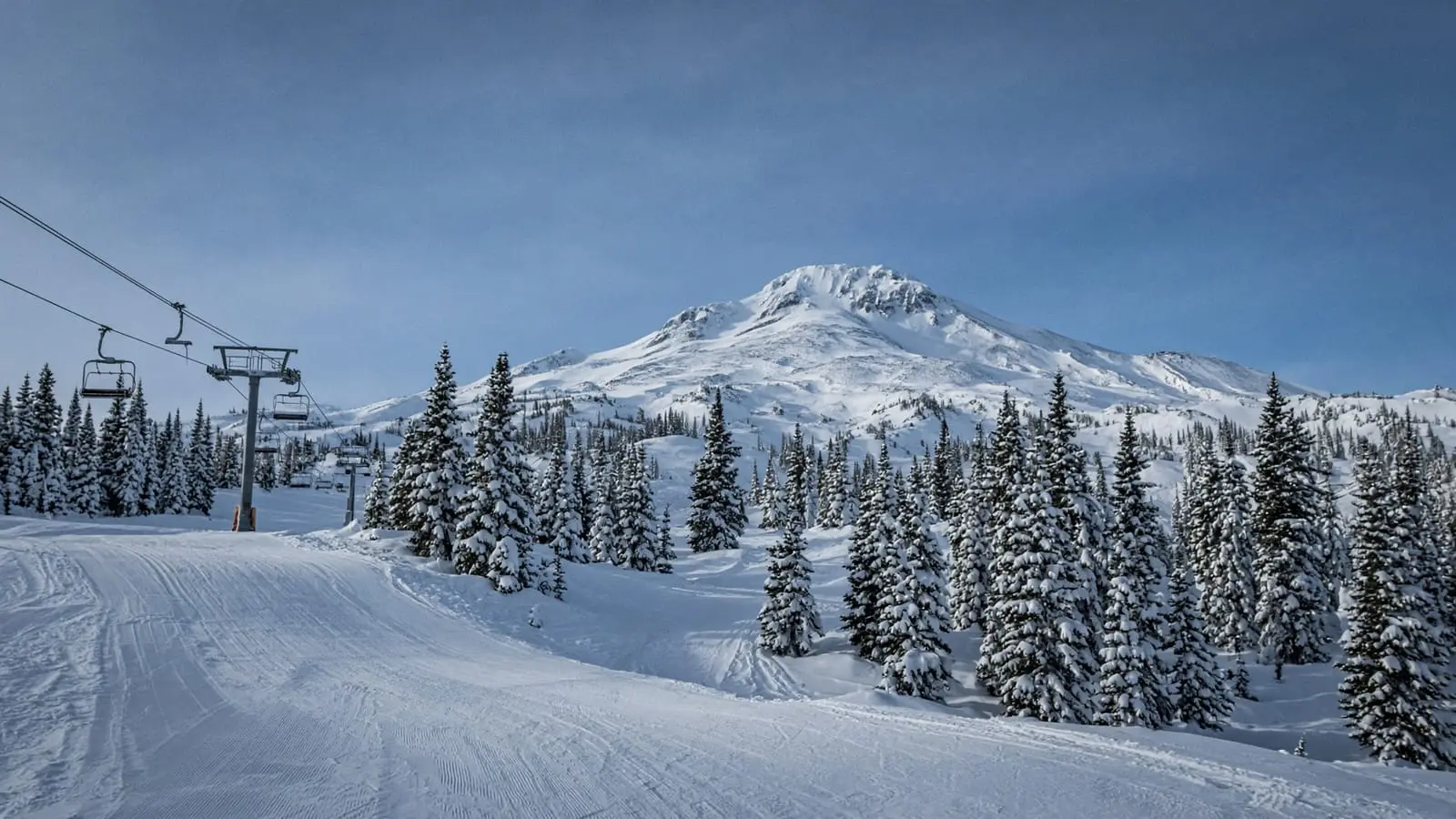 A chairlift and snow-covered trees below a Cascade peak